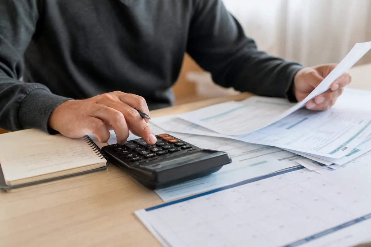 Pessoa confere parcelas atrasadas de pensão com calculadora e calendário