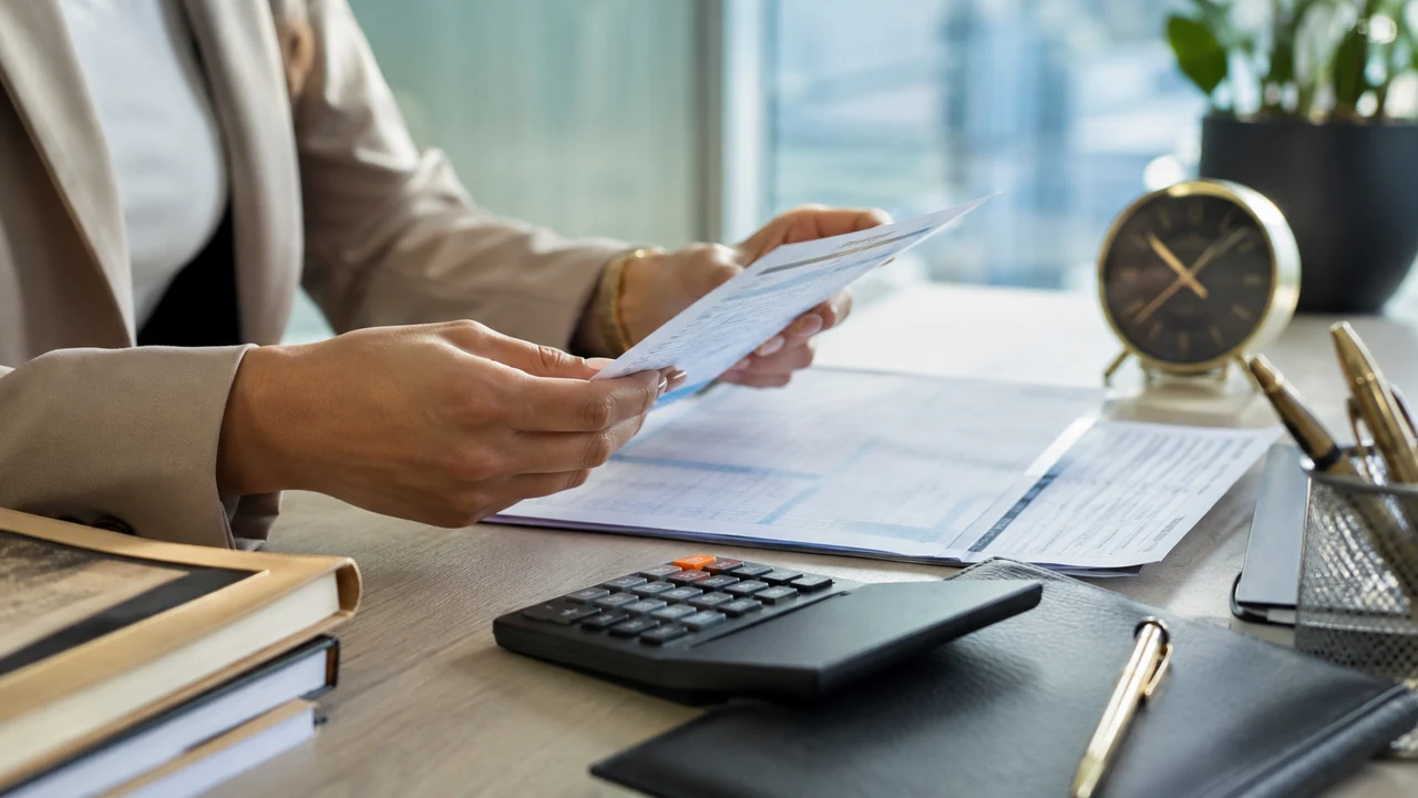 Trabalhadora confere contracheque e horas extras com calculadora