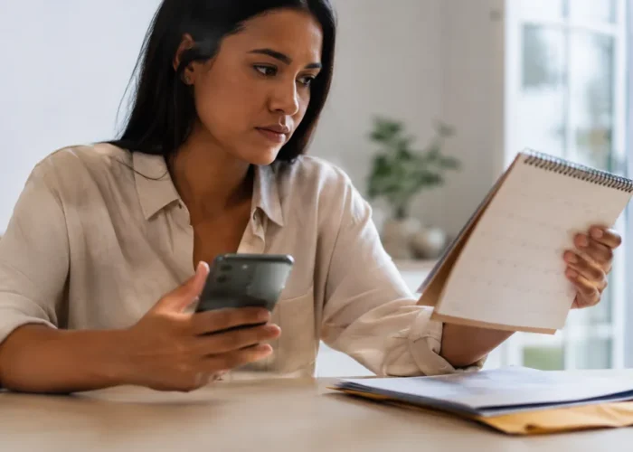 Trabalhadora confere calendário e celular após rescisão não paga