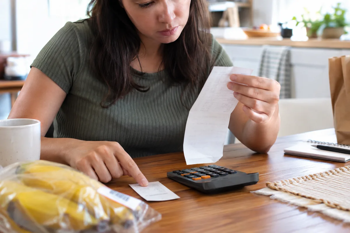 Consumidora compara recibo, etiqueta e calculadora após cobrança errada