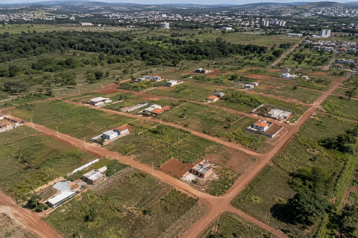 Vista aérea de loteamento com vias de terra, lotes e casas em implantação